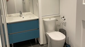 Un baño moderno con un lavamanos blanco, un mueble azul y un inodoro.