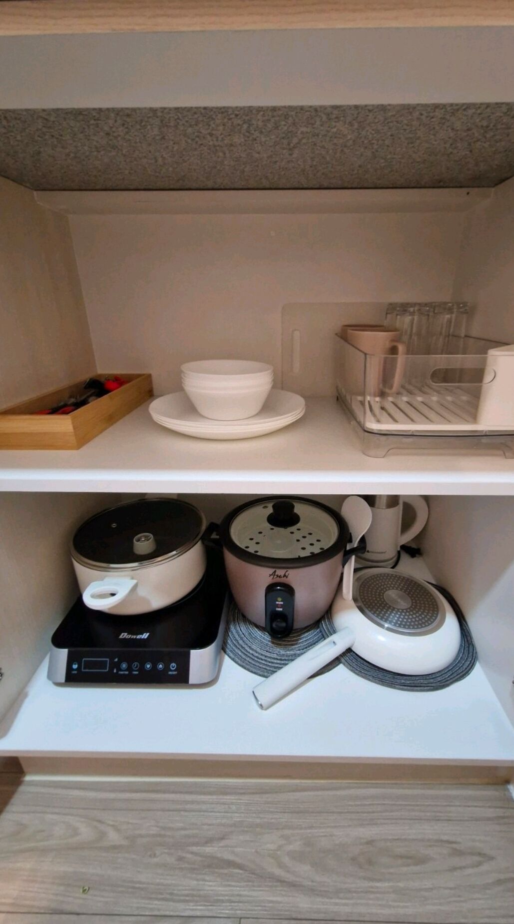 A kitchen area with a countertop, a rice cooker, a coffee maker, and a drawer with utensils.