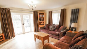 Ein Wohnzimmer mit einer Couch, einem Couchtisch, einem Bücherregal und einer Lampe.