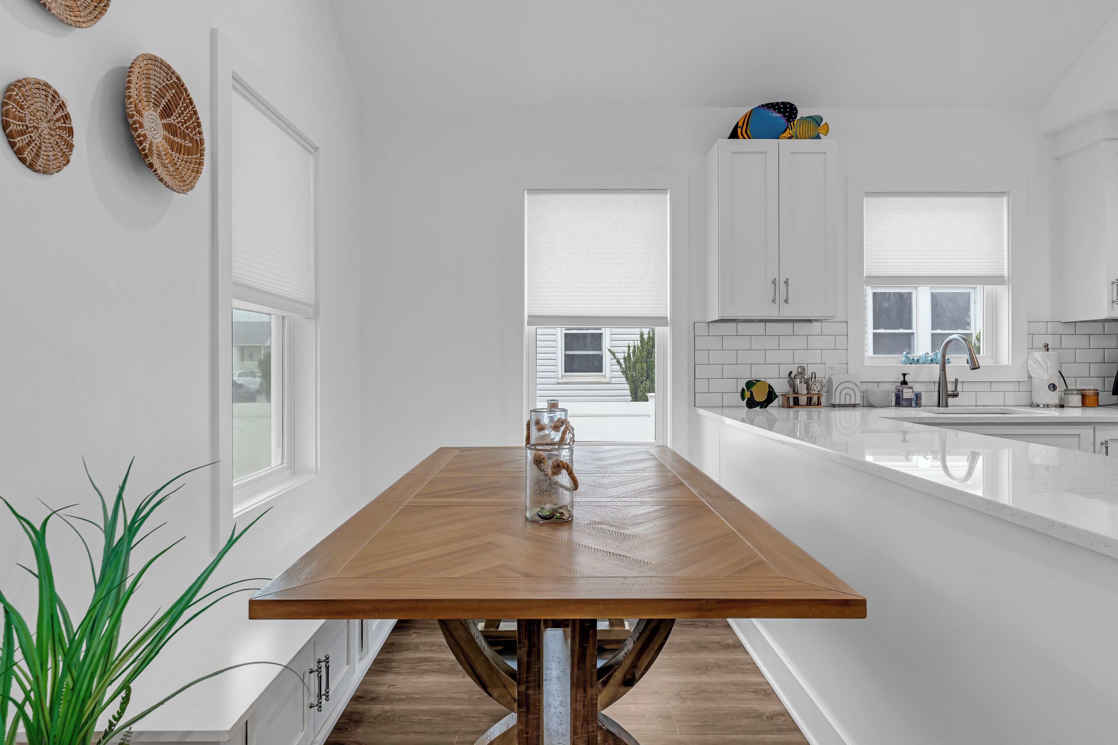 Een moderne keuken met een houten eettafel, witte kastjes en een groot aanrechtblad met spoelbak.