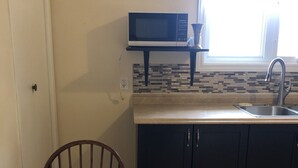 A compact kitchen with a microwave on a shelf, a sink, and a window above the counter. - Downtown walkable to restaurants, bars public transportation and the waterfront. (Charlottetown)