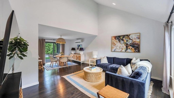 A modern living room with a dark blue sofa, a round coffee table, and a large abstract painting on the wall.