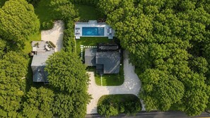 A residential property with a swimming pool, a covered patio, and a large lawn.