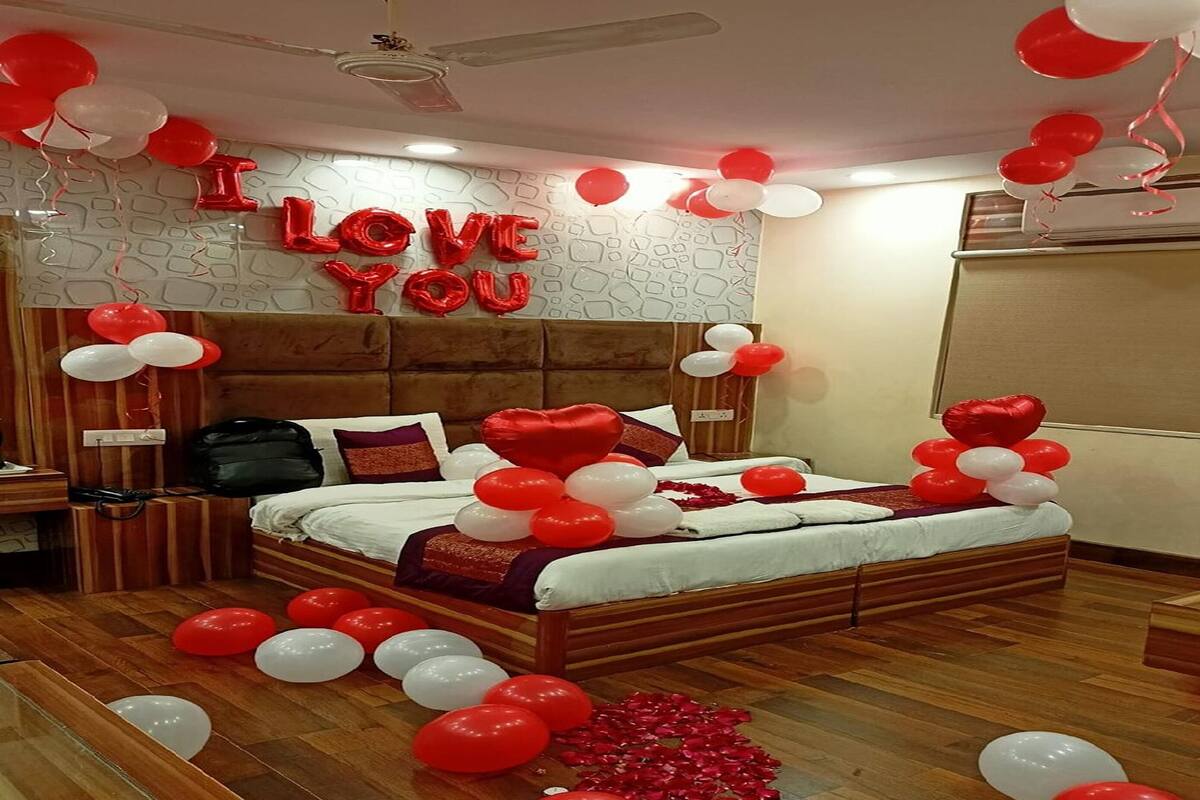 Un dormitorio con cama, mesita de noche, cómoda y una pared decorada con globos que dicen 'I LOVE YOU'.