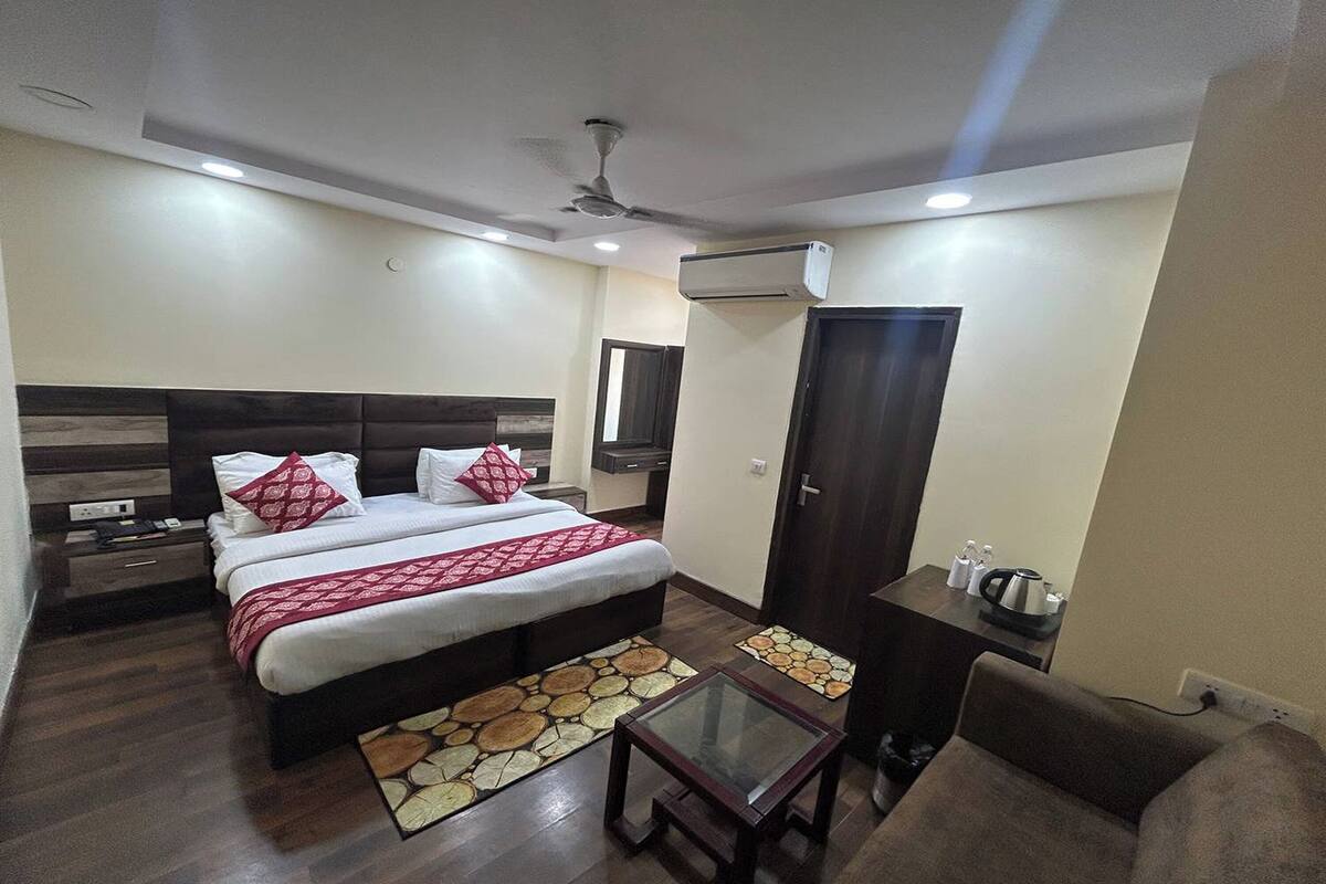 Una habitación de hotel con una cama, una mesita, un sofá y un armario.
