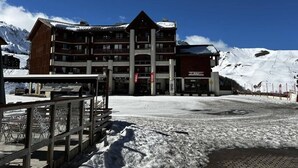 A multi-story building with a ski lift in the background, surrounded by snow-covered mountains. - Ski-in/ski-out & foot of the slopes, 3rd floor, balcony, tv, ski locker, 30m², La Plagne (La Plagne)