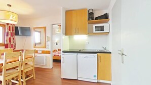 A compact kitchen with wooden cabinets, a microwave, and a dishwasher.