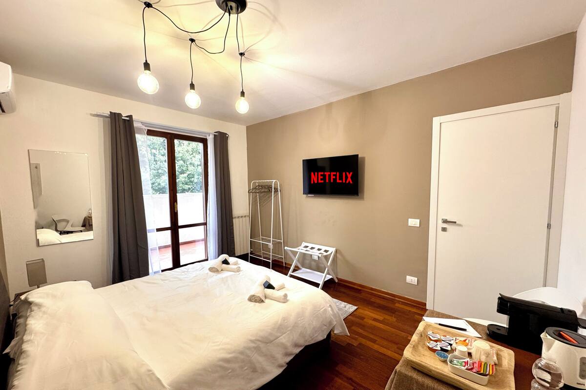 Une chambre d’hôtel équipée d’un lit, d’un téléviseur affichant le logo « NETFLIX », d’un espace douche et d’une table en bois avec des articles de toilette.
