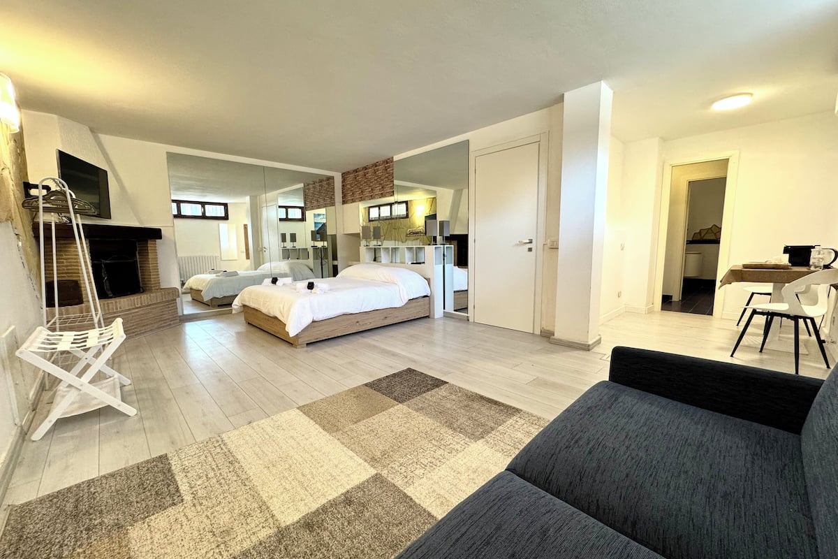 Une chambre d’hôtel moderne dotée d’un grand lit, d’un canapé, d’un coin repas et d’une cheminée.