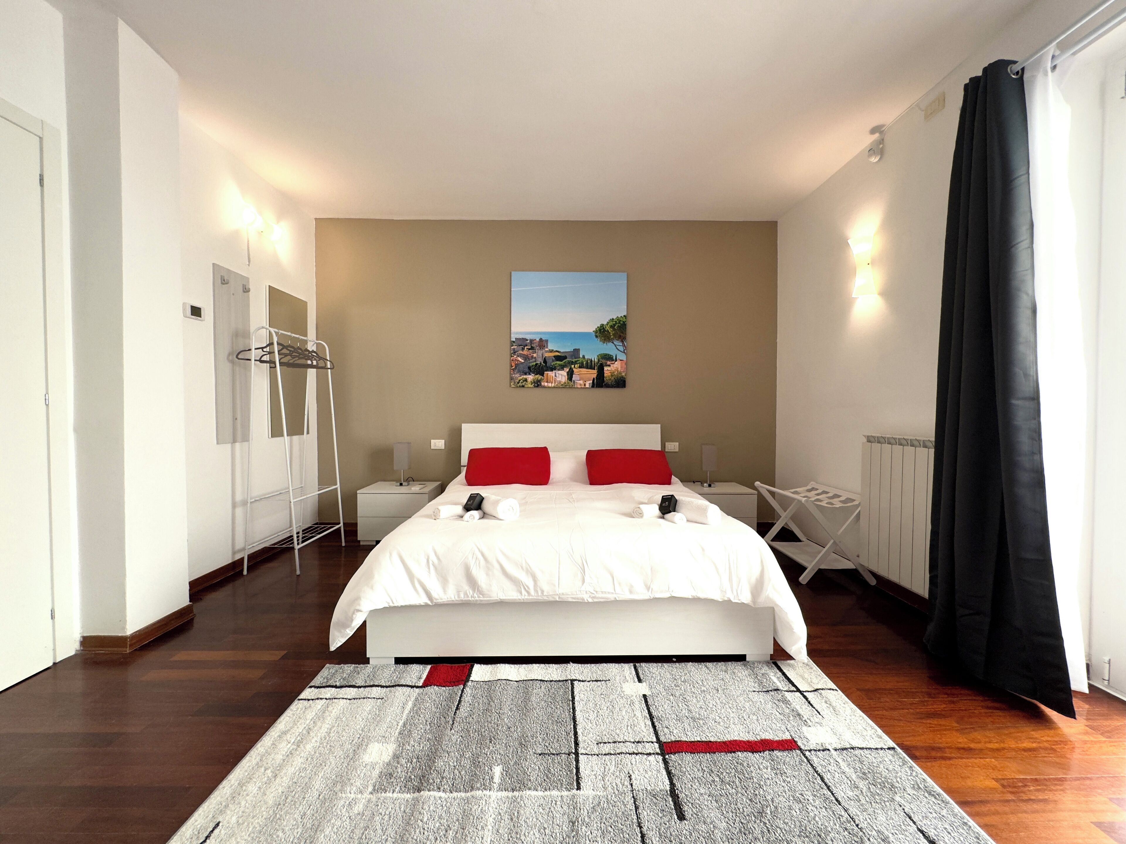 A modern hotel room with a large bed, a view of the city, and a radiator.
