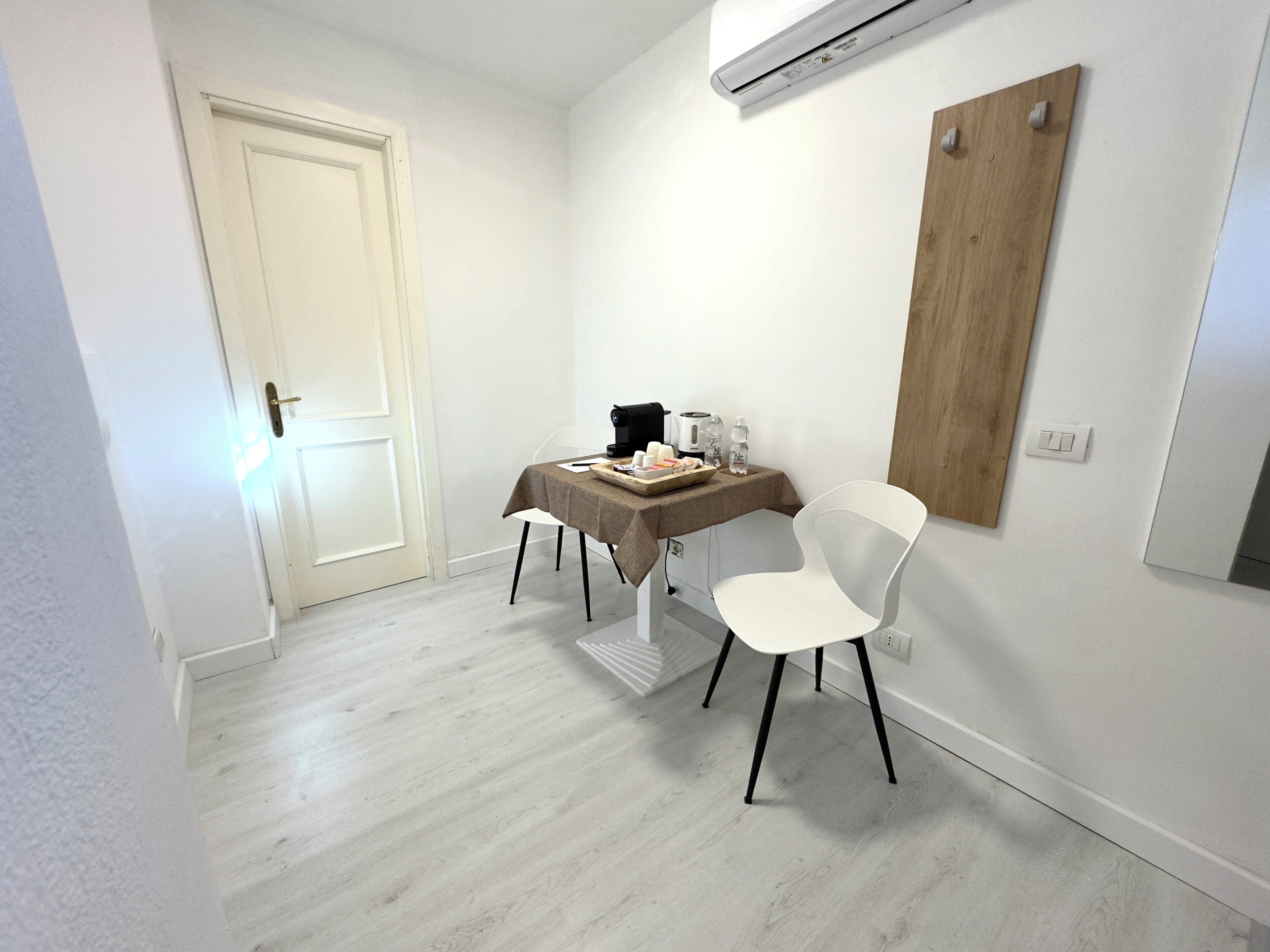 A small, clean room with a table, a chair, and a coffee maker.