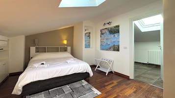 Un dormitorio con tragaluz, una cama, una mesita de noche, una lámpara de pared y un radiador.