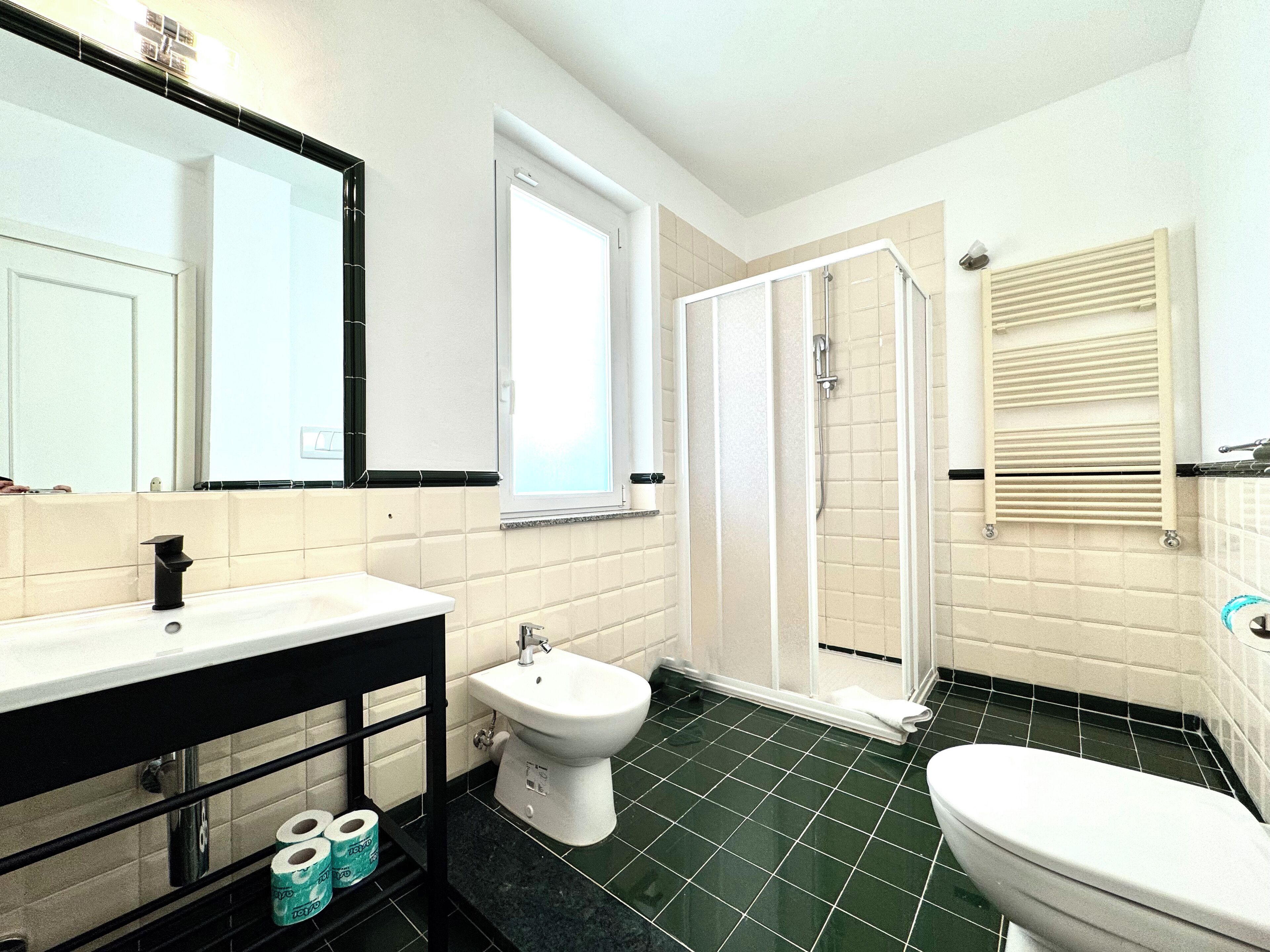 Un baño con inodoro, bidé, lavamanos y ducha.