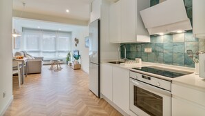Una cocina moderna con armarios blancos, encimera negra y salpicadero verde.