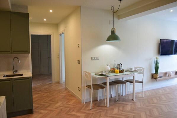 Una cocina moderna con comedor, suelo de madera en espiga y un televisor montado en la pared.