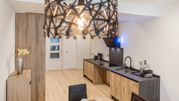 A modern kitchen with a central island, a built-in oven, and a pendant light fixture. - Spacious apartment 9 min from the beach (Gijon)