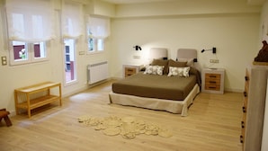 A bedroom with a large bed, bedside tables, a wooden bench, and a patterned rug. - Spacious apartment 9 min from the beach (Gijon)