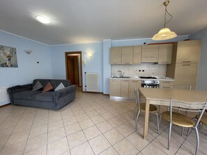 A compact living space with a kitchenette, a dining area, and a sofa. - 001-2 Residence Valentino 2 (Giustino)