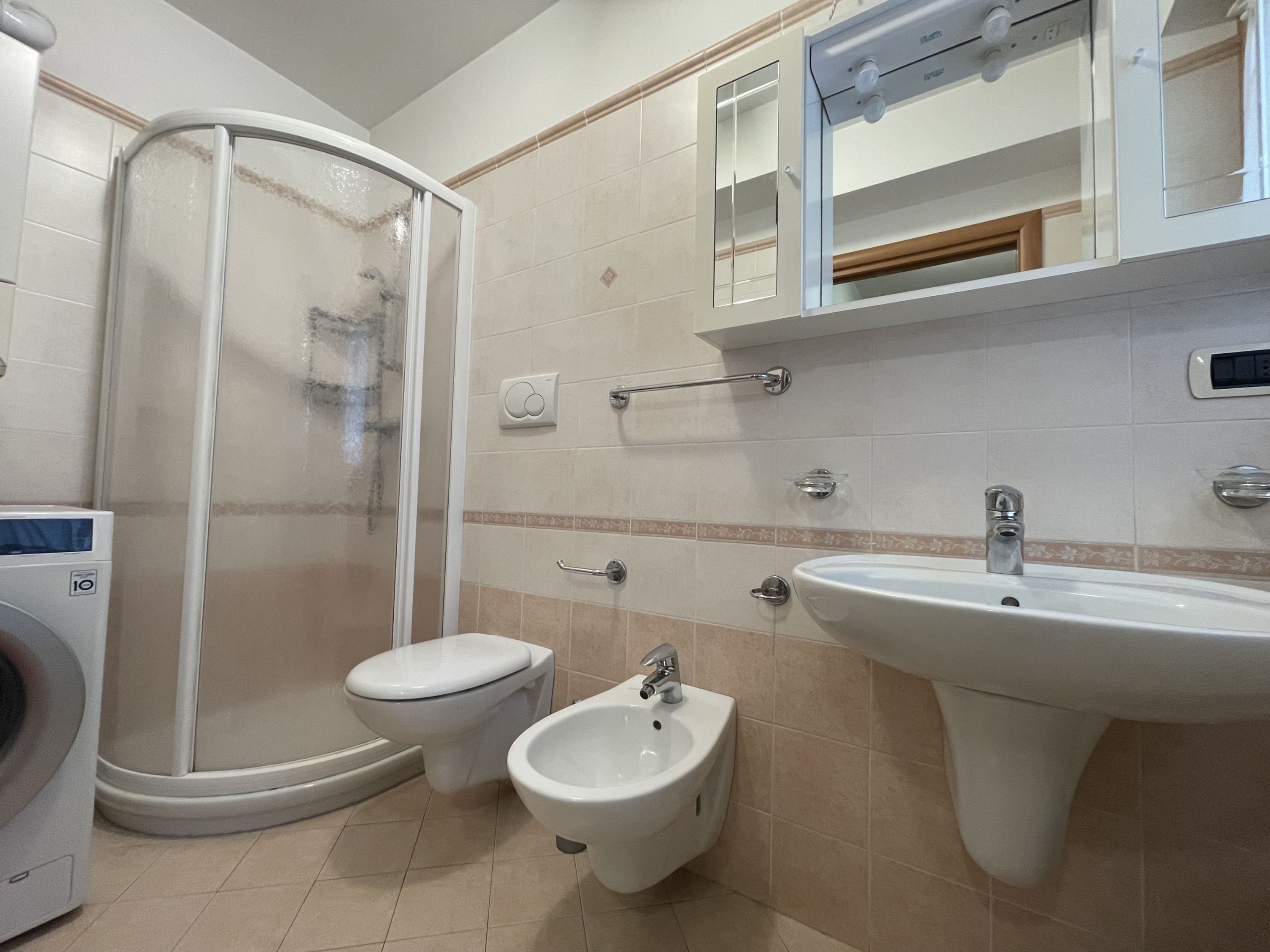 A bathroom with a glass-enclosed shower, a toilet, a bidet, and a sink.