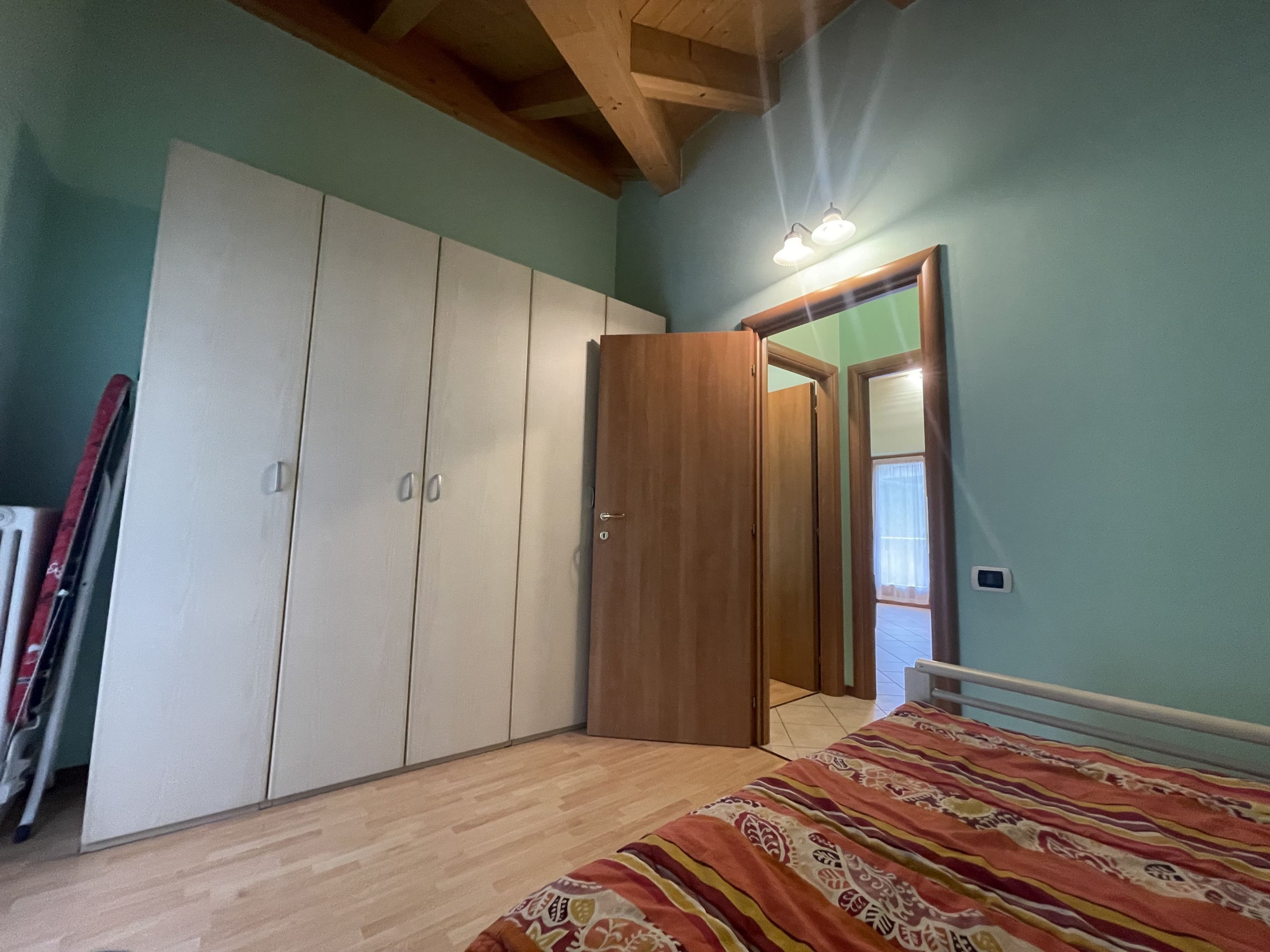 Une chambre à coucher comprenant un lit, une armoire et une porte donnant sur une autre pièce.