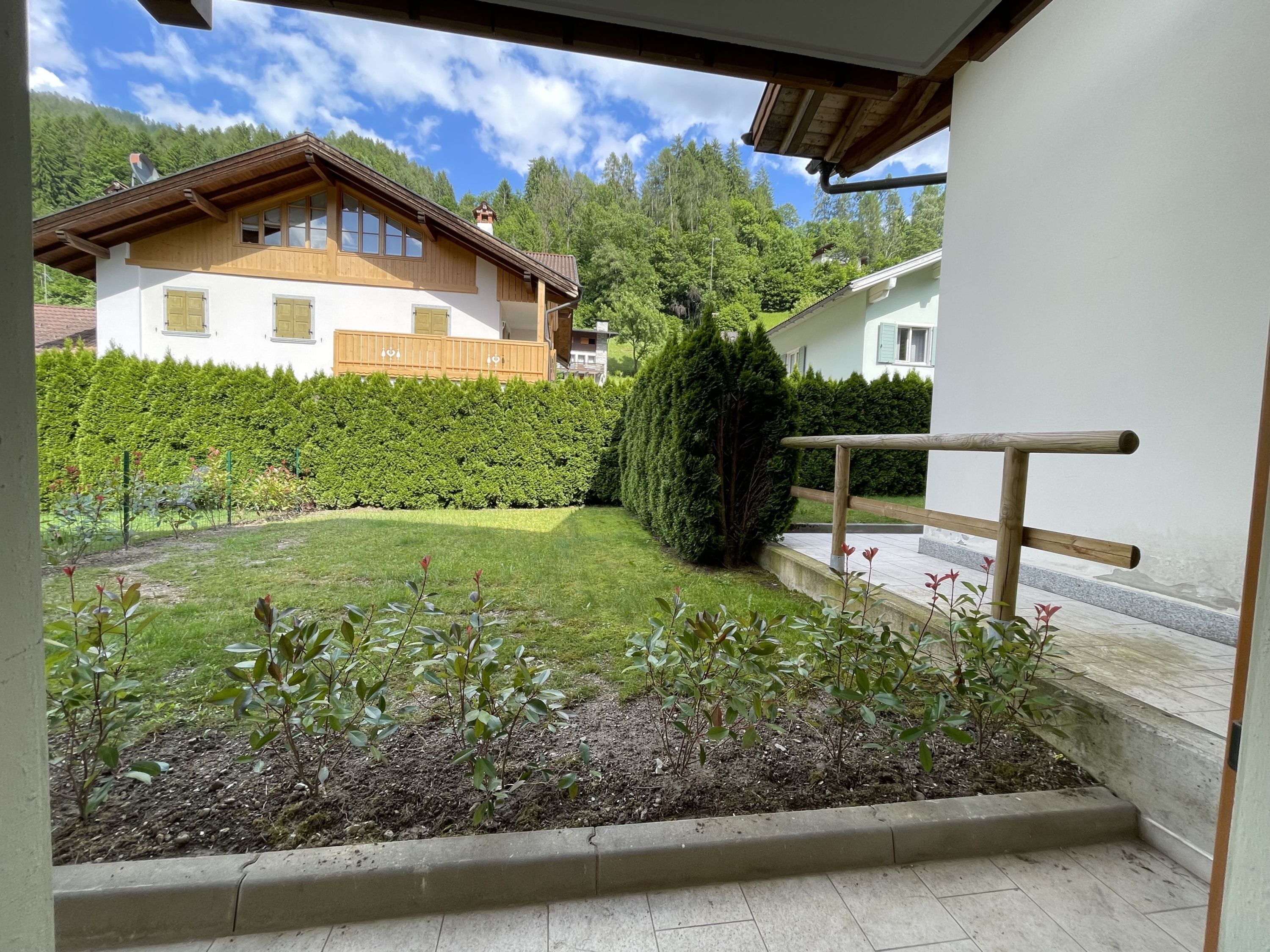 Il s’agit d’une propriété résidentielle dotée d’un jardin bien entretenu, d’un balcon en bois et offrant une vue sur les maisons voisines.