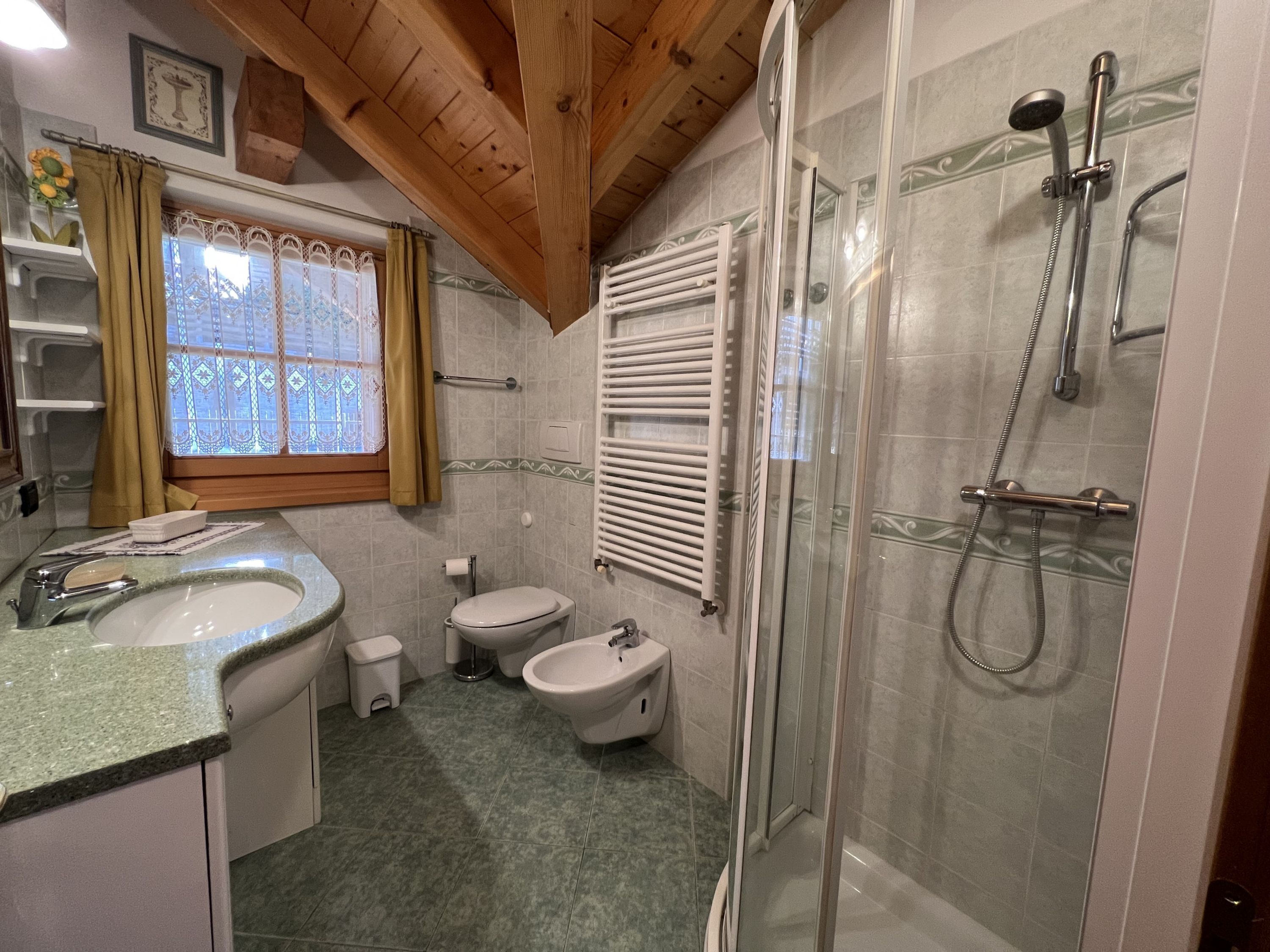 A bathroom with a shower, toilet, bidet, and sink.