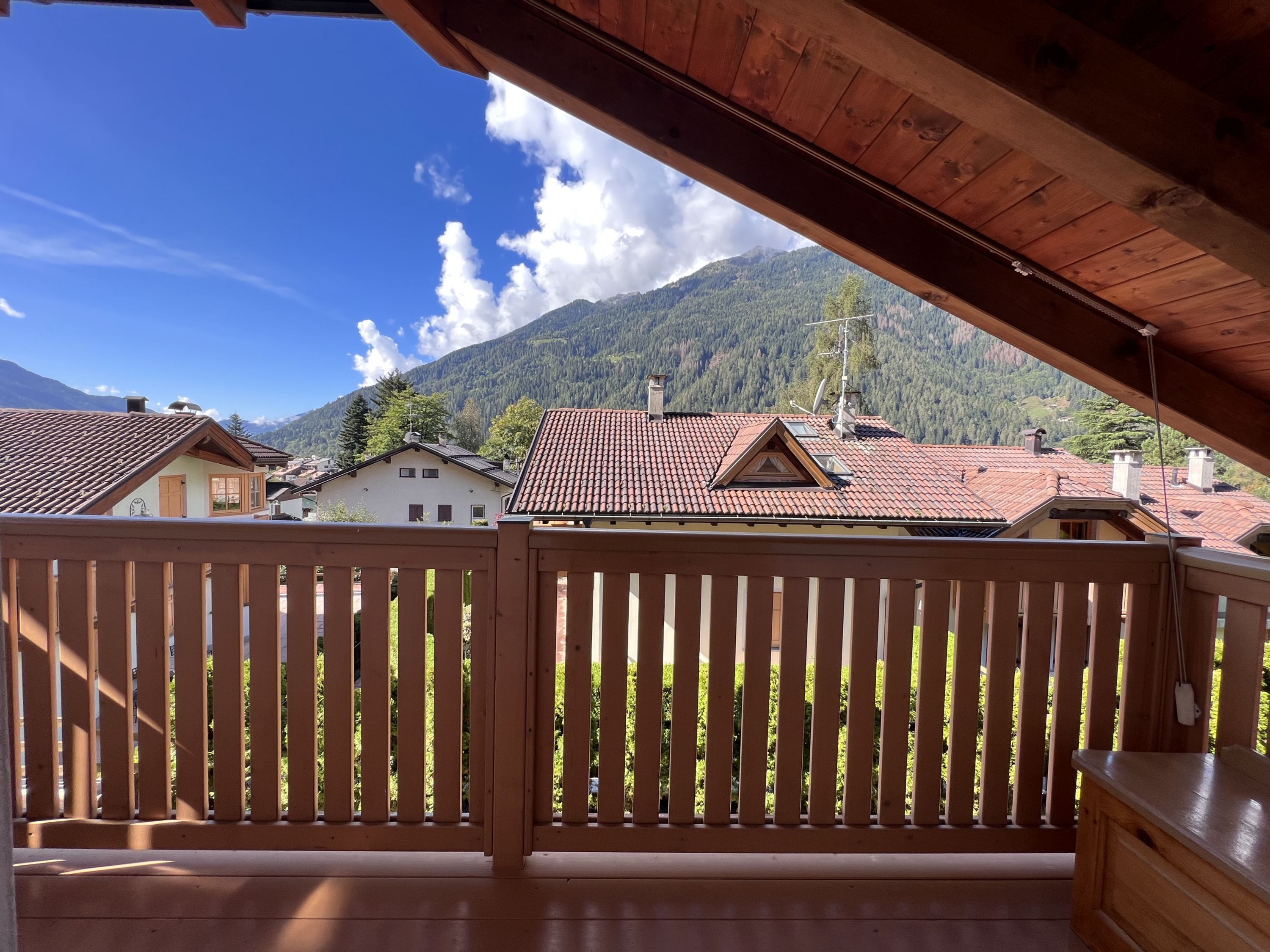 A wooden balcony with a view of houses and mountains.