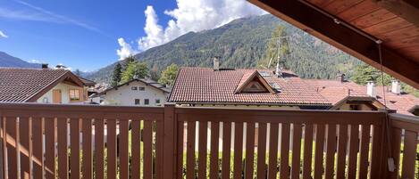 A wooden balcony with a view of houses and mountains.
