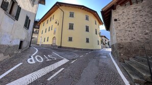 A cobblestone street with a yellow building, a stop sign, and stone steps leading up to a building. - 007 Trilocale con Giardino Giustino (Giustino)