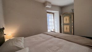 A bedroom with a bed, a nightstand, a lamp, and a wardrobe. - 007 Trilocale con Giardino Giustino (Giustino)