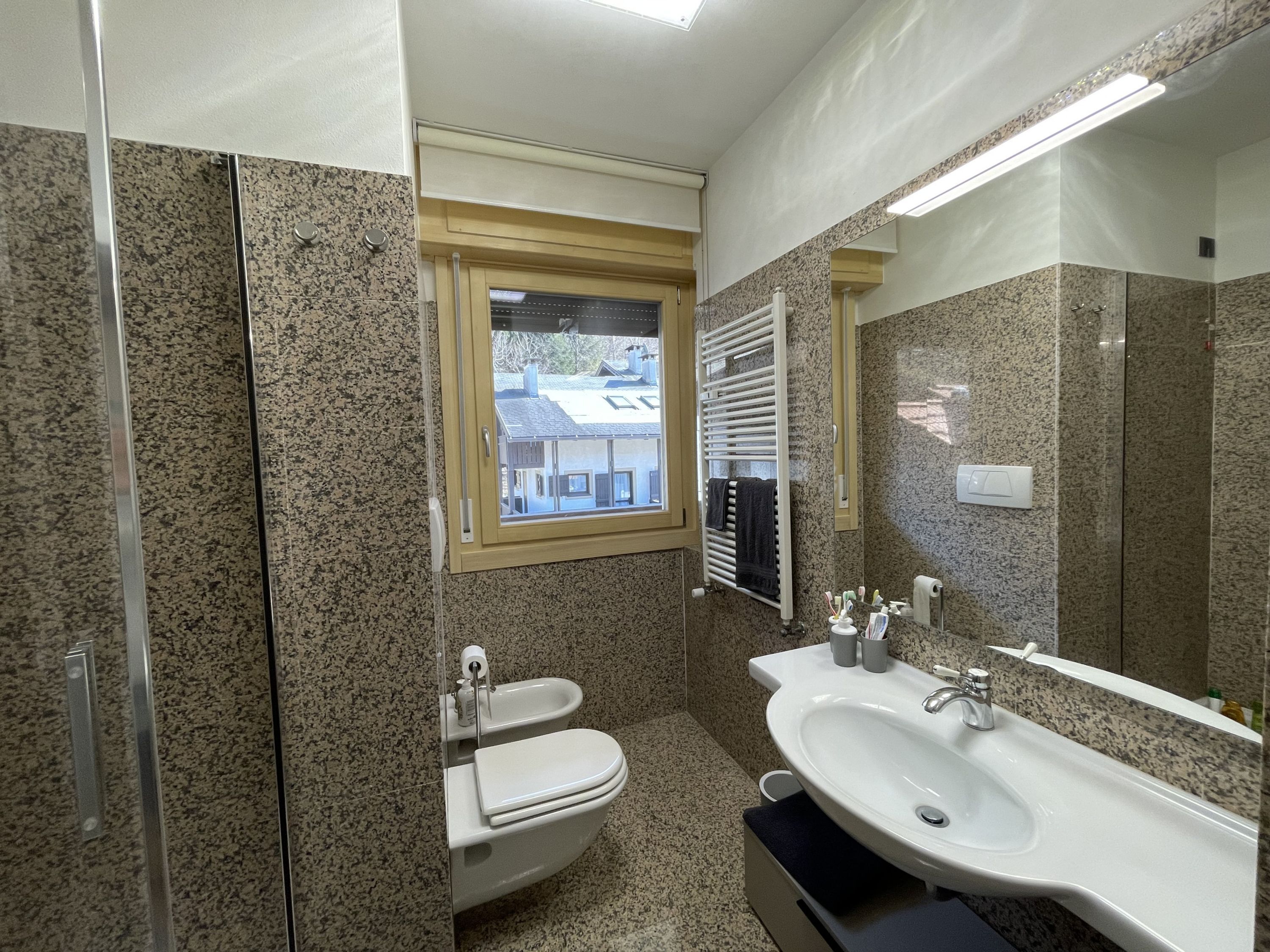 A bathroom with a toilet, bidet, sink, and a large mirror.
