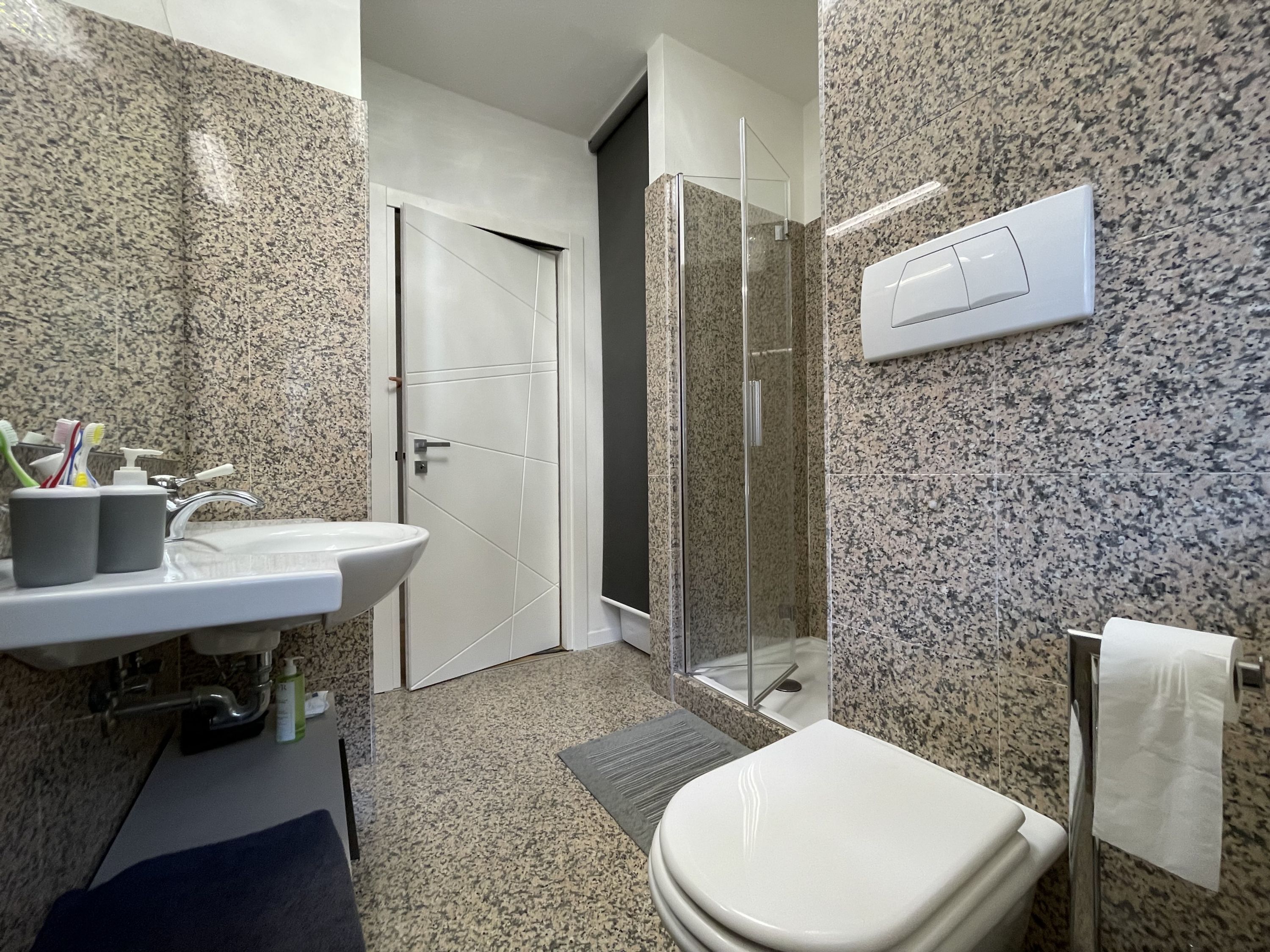 A modern bathroom with a sink, toilet, and glass shower enclosure.