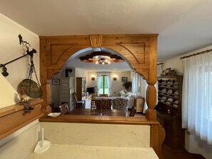 A spacious living area with a wooden ceiling, a dining table, and a kitchen in the background. - 059 Quadrilocale Piano Terra Pinzolo (Pinzolo)