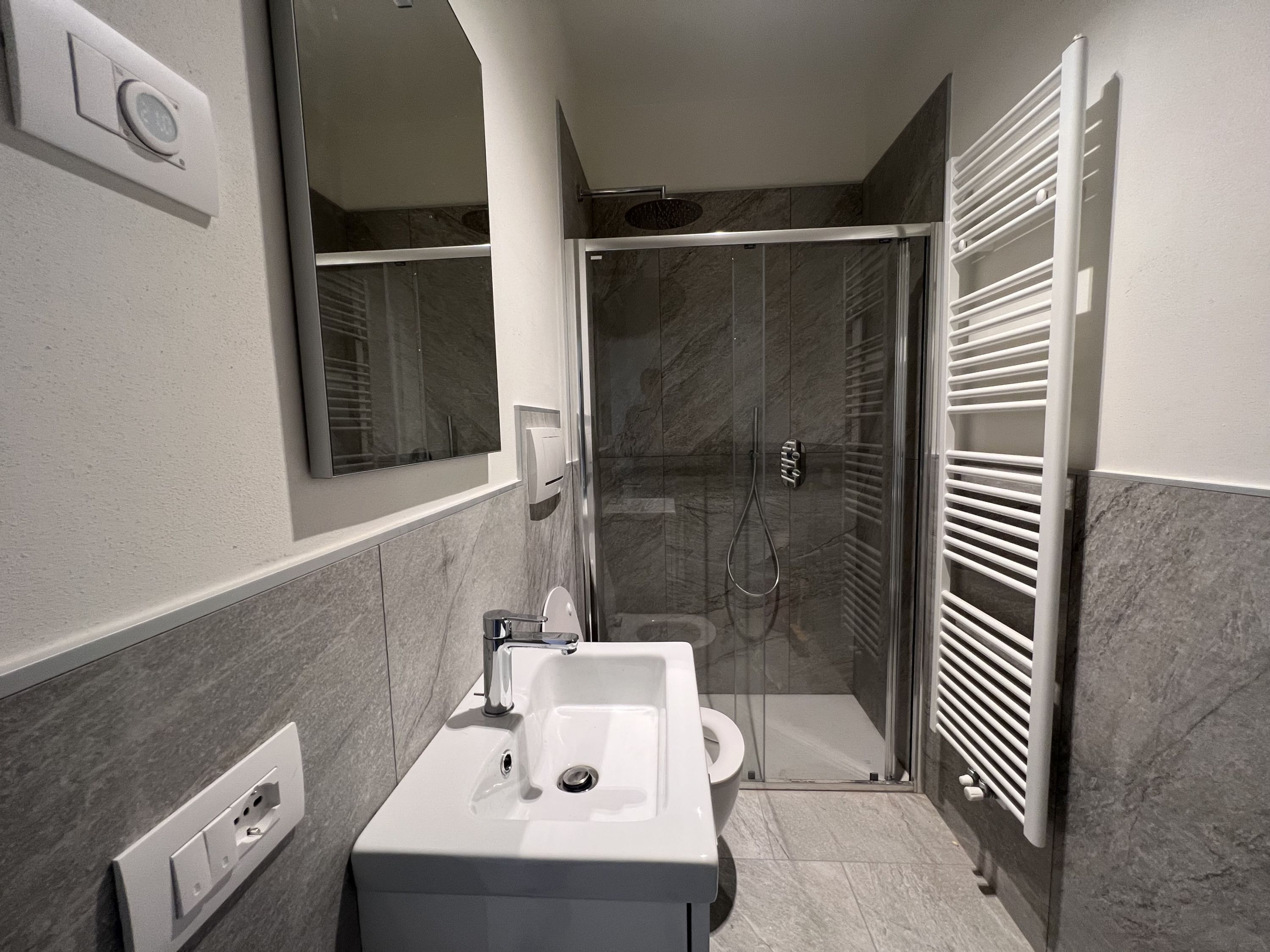 A modern bathroom with a shower, toilet, and sink.