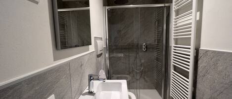 A modern bathroom with a shower, toilet, and sink.