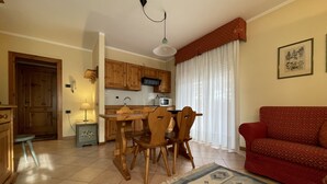 Un espacio habitable compacto con cocina, comedor y un sofá rojo.