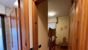 Un pasillo con puertas de madera, una litera y una silla.