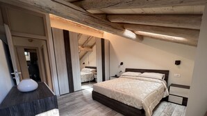 Une chambre à coucher avec un plafond en bois, un lit recouvert d’une couvre-lit à motifs, une table de chevet et une petite table de nuit.