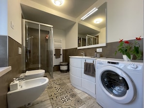 Un baño moderno con bañera, inodoro, ducha y lavadora incorporada.