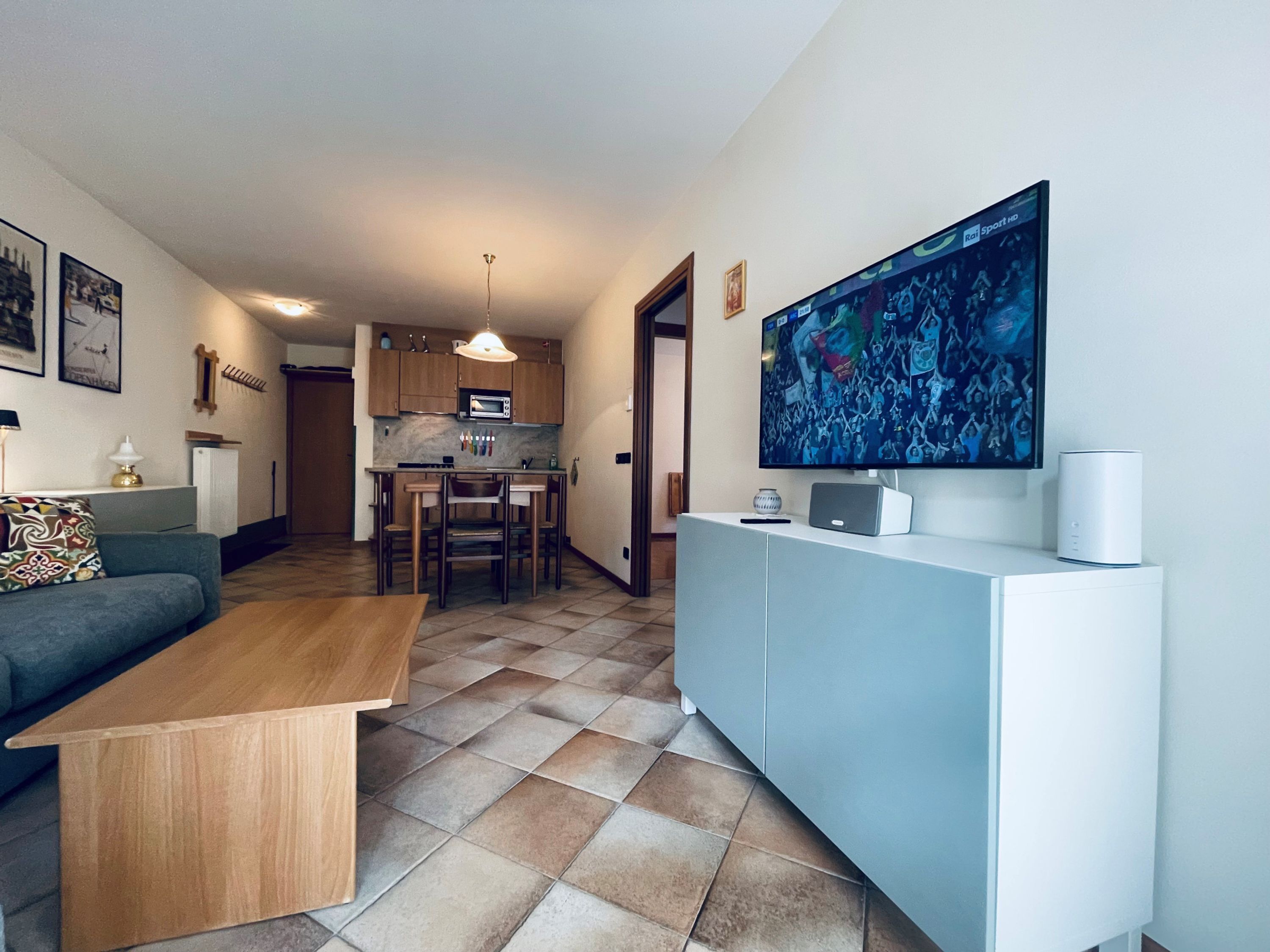 A modern living room with a sofa, coffee table, and a flat-screen TV mounted on the wall.