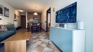 Un soggiorno moderno con un divano, un tavolino da caffè e una televisione a schermo piatto montata a parete.