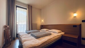Una camera d'albergo con un letto grande, una testiera in legno, un comodino e una finestra con tende.