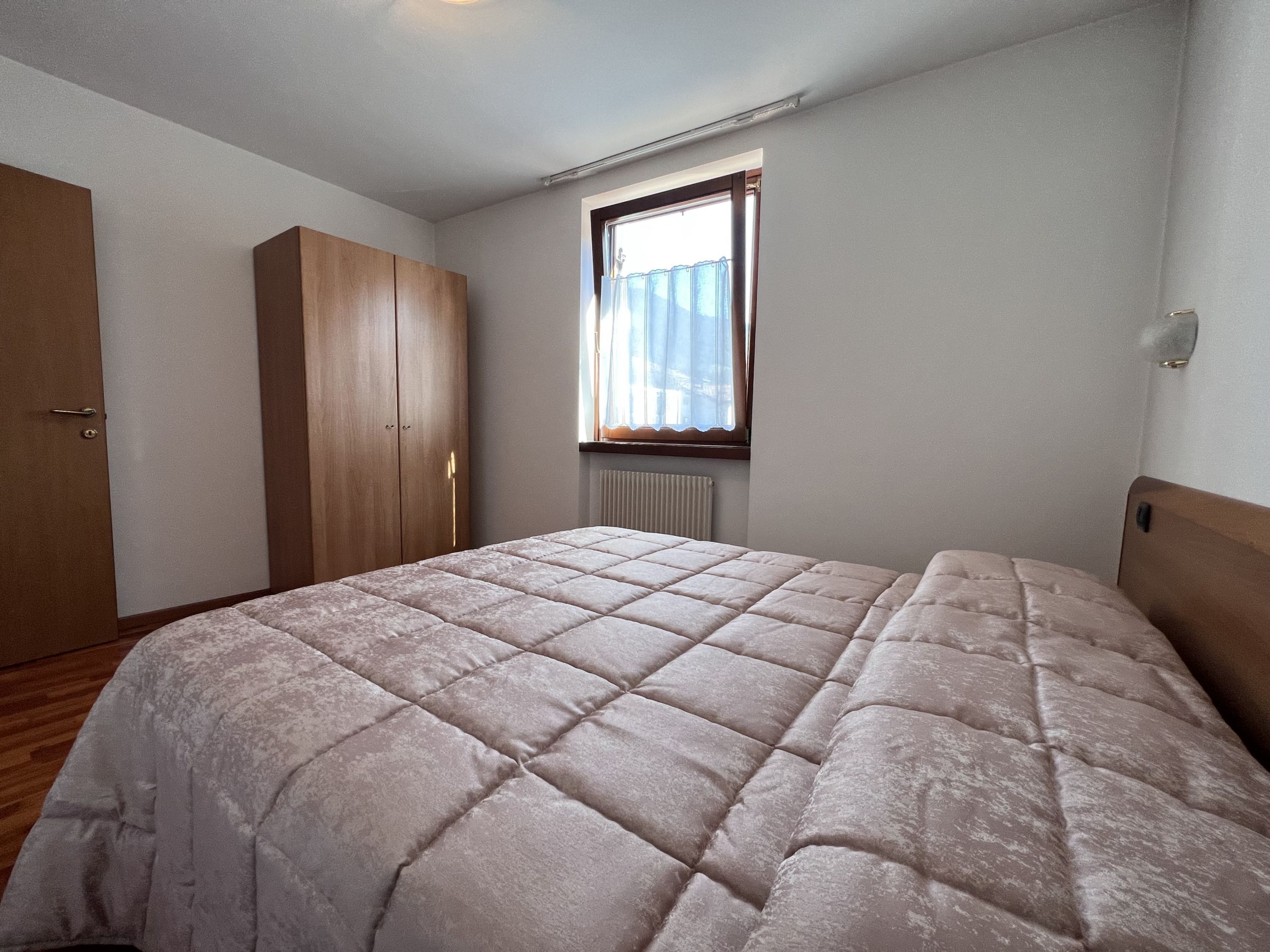 Una camera da letto con un letto, un armadio e una finestra.