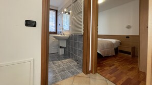 Een knus slaapkamer met houten vloer, een bed met hoofdbord en een klein nachtkastje.