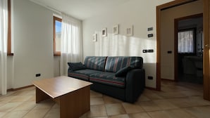 Een woonkamer met een bank, een salontafel en een deur naar een badkamer.