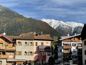 Une ville de montagne aux bâtiments traditionnels en bois, une enseigne indiquant « Al Borco Antico », et des montagnes enneigées en arrière-plan.