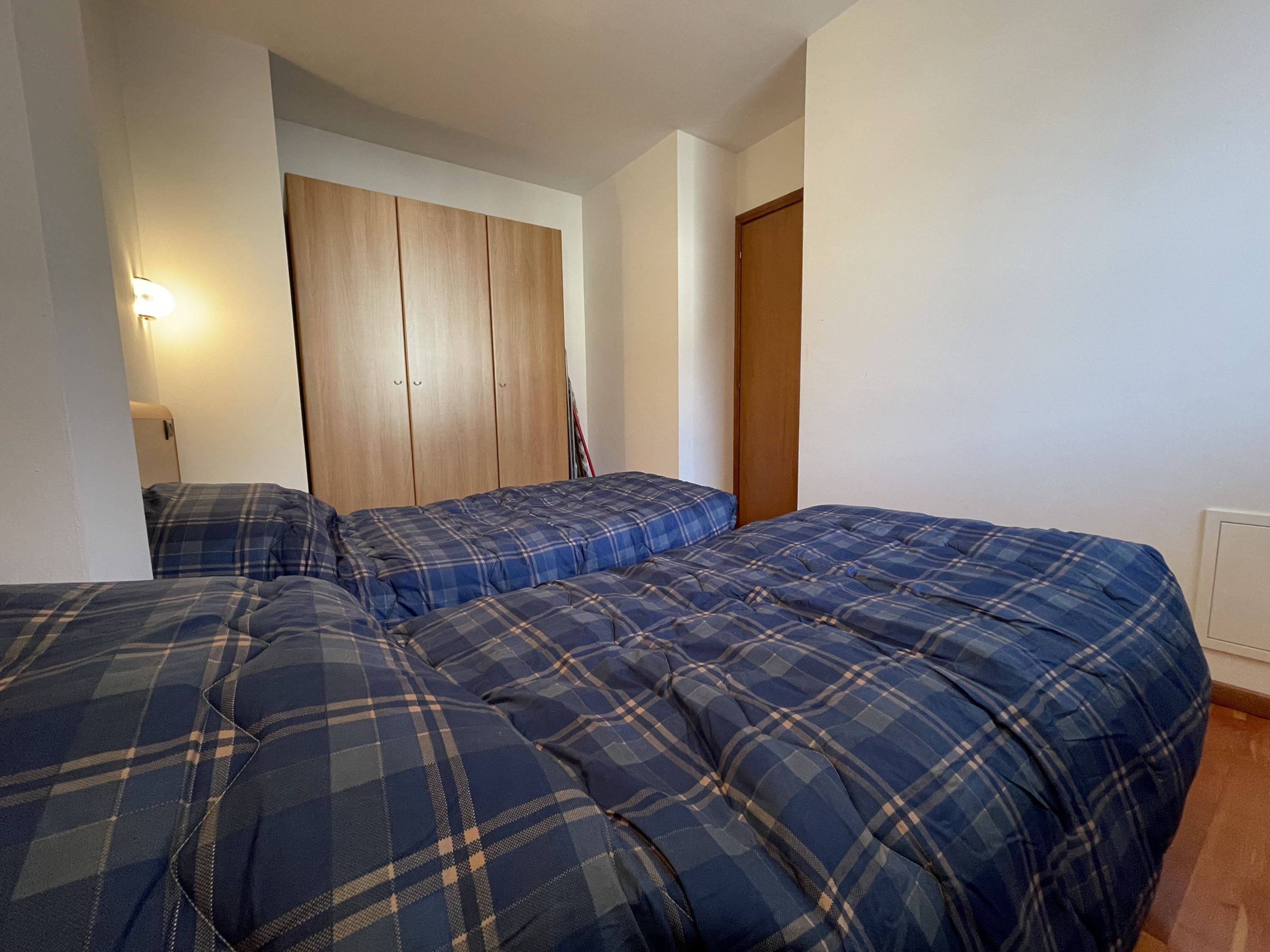 Une chambre avec deux lits, une armoire et une porte.
