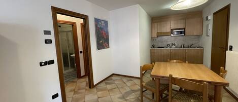 A compact kitchen with wooden cabinets, a microwave, and a dining area with a wooden table and chairs.