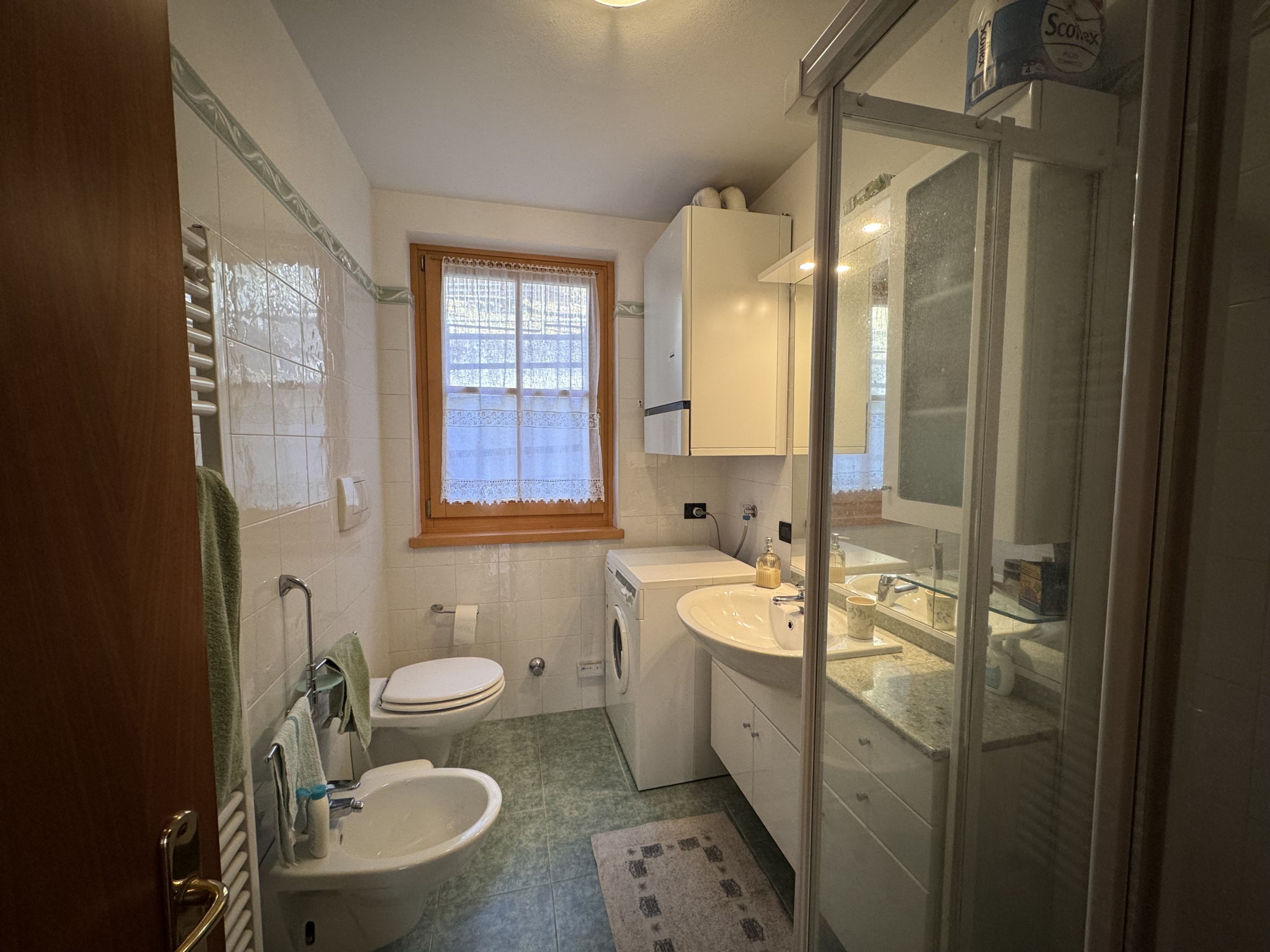 Un baño pequeño con inodoro, bidé, lavamanos y cabina de ducha de vidrio.