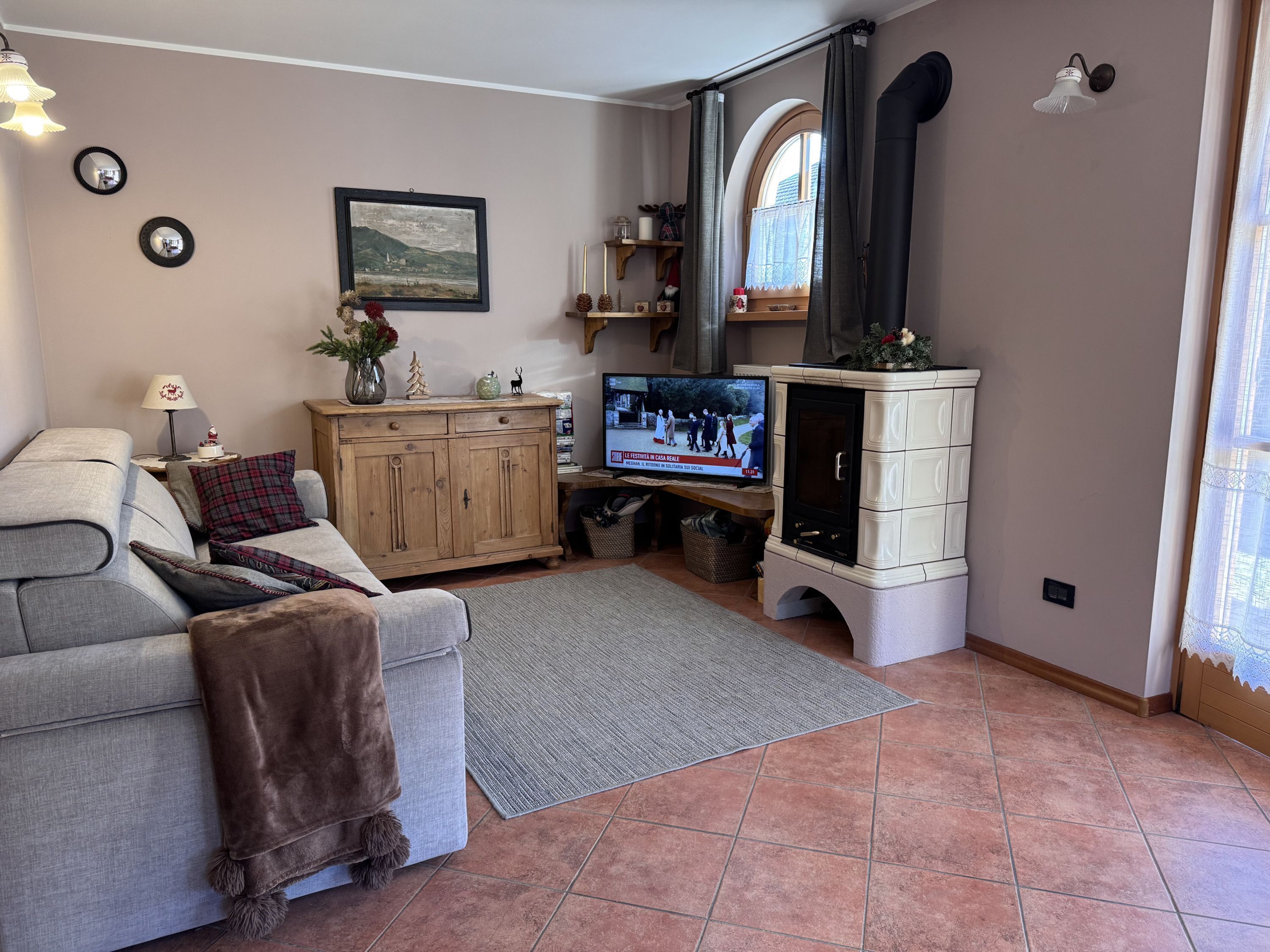 A cozy living room with a grey sofa, wooden cabinet, and a television.